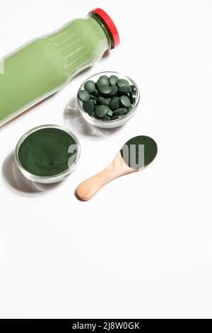 green smoothie in bottle and spirulina algae powder and pills in glass bowl on white background.useful habits,self care and healthy lifestyle concept. Stock Photo