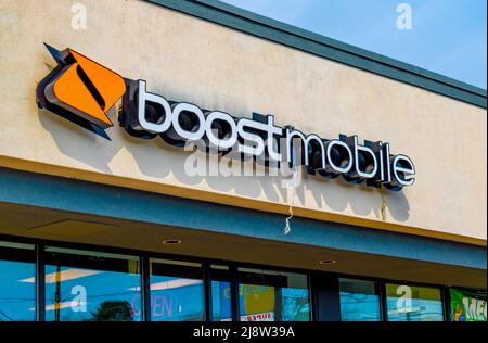 Outside, 'Boost Mobile' facade brand and logo signage above glass windows in soft early morning light on a sunny day with orange logo in Charlotte, NC. Stock Photo