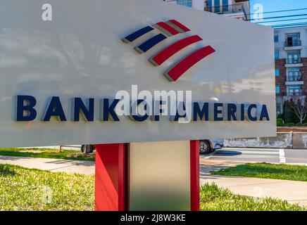 Outdoor, free standing 'Bank of America' brand and logo sign in red, white and blue with greenery and reflections on a sunny day. Stock Photo