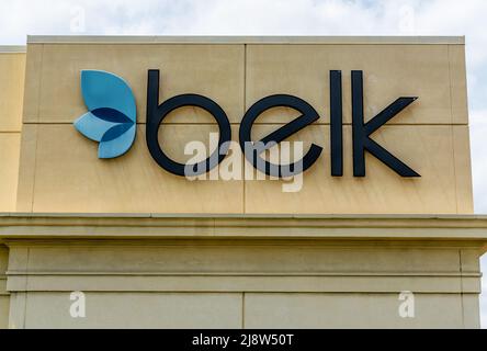 'Belk' department store's exterior facade brand and logo signage in black letters with blue logo on beige stone building with sky at Southpark Mall. Stock Photo