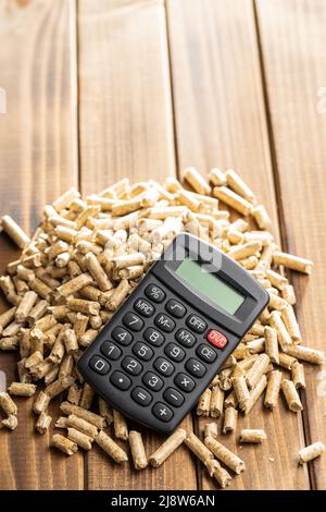 Wooden pellets and calculator, biofuel on a wooden table. Ecologic fuel made from biomass. Renewable energy source. Stock Photo