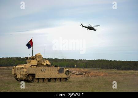 Drawsko Pomorskie, Poland. 17th May, 2022. U.S. Army Col. Stephen Capehart, the commander of 3rd Armored Brigade Combat Team, 4th Infantry Division observes exercise Defender Europe 22 from his M2A3 Bradley Fighting Vehicle as a Polish Mil Mi-24 Hind attack helicopter flies over a company of U.S. Army M1A2 Abrams tanks at Drawsko Pomorskie Training Area, May 17, 2022 in Drawsko Pomorskie, Poland. Credit: Capt. Tobias Cukale/U.S Army/Alamy Live News Stock Photo