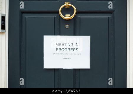 Meeting in progress sign attached to a domestic house front door presumably where somebody is Working From Home WFH or in a hybrid job. UK (130) Stock Photo