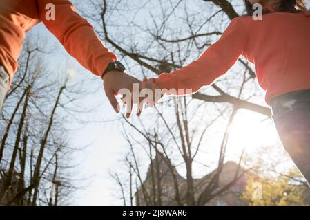 Couple hold hands in the autumn or summer park on sunset. Closeup of loving couple holding hands while walking. Stock Photo