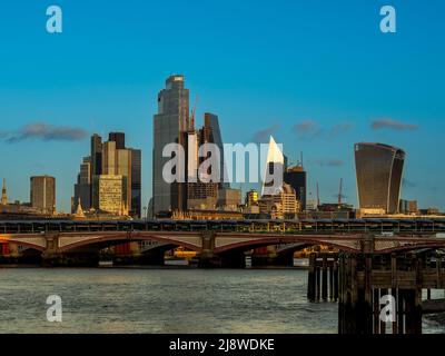 Blackfriars bridge crossing the river Thames with modern tower blocks in the distance, seen against a blue sky at dusk. London UK. Stock Photo