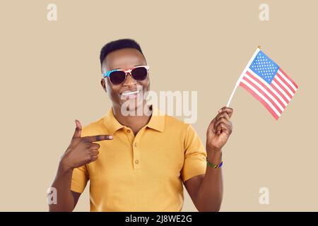 Happy African man who got US citizenship smiles and points at American flag in his hand Stock Photo