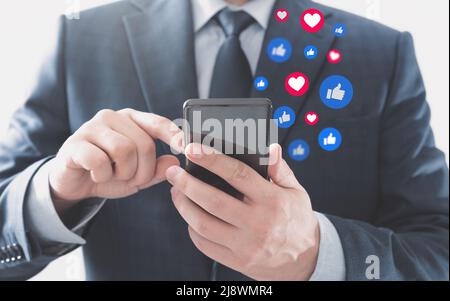 Businessman using social media. Icons flying from the smartphone. Stock Photo