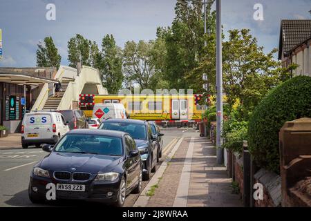 Hoylake Train Station, barriers down with train passing through the station Stock Photo