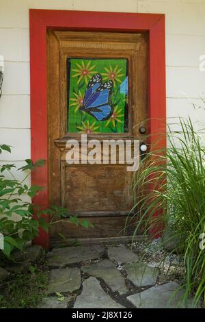 Colourful side entrance door on car garage building with white wood plank cladding. Stock Photo