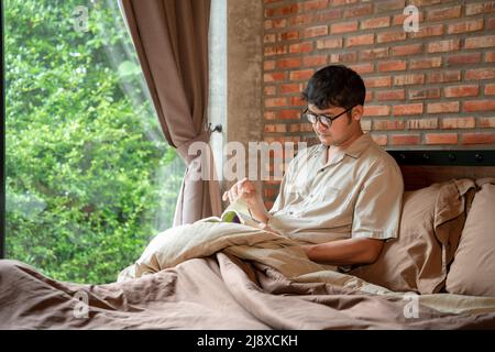 A man reading book in the bedroom at home. Stock Photo