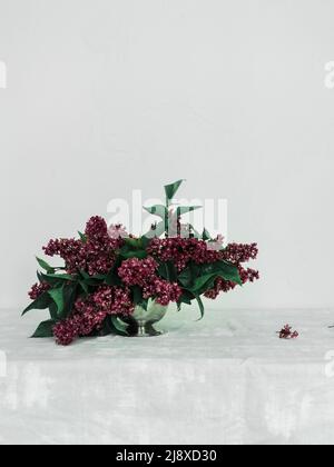 purple lilacs arranged as a centerpiece at a dinner table for a fine art wedding Stock Photo