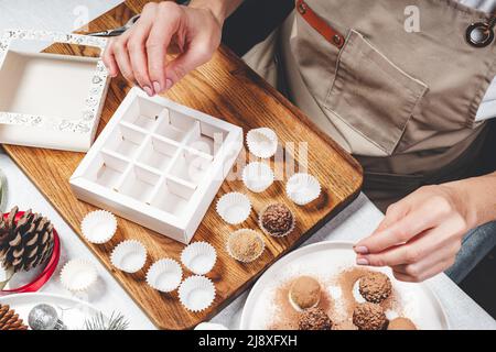 Woman confectioner make premium hand-crafted chocolate truffles. Close-up of female hands and delicious chocolates. Handmade candy. Top view Stock Photo