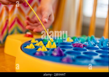 Children's game of using a miniature pole and line lowered into open  plastic fish to catch them as the pond spins Stock Photo - Alamy