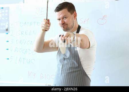 Standing man hold sharp kitchenware for cooking, knife sharpening on kitchen Stock Photo