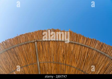 Beach palm umbrella, bottom view against the blue sky. Stock Photo