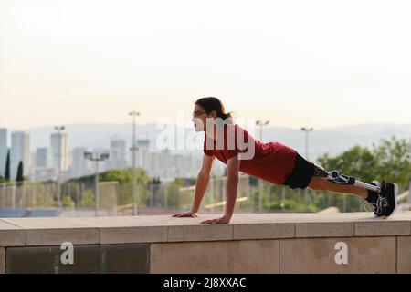 Young male athlete with a disability doing push ups while exercising outdoors. Stock Photo