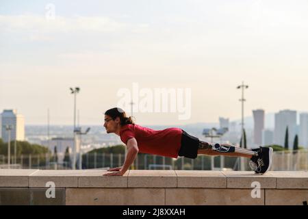 Young male athlete with a disability doing exercise outdoors. Stock Photo