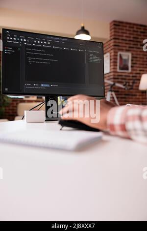 Selective focus on computer screen of african american programmer working remote from home developing software on pc. System developer writing code on personal computer typing algorithm on keyboard. Stock Photo