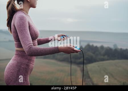 Side View of Unrecognisable Young Woman Holding Skipping Rope, Girl Working Out Outdoors on the Hill Stock Photo