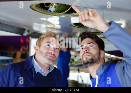 two modern mechanics working in hangar Stock Photo