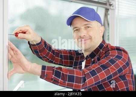 worker fasten the handle to a plastic window Stock Photo
