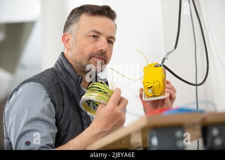 electrician checking socket voltage using multimeter Stock Photo