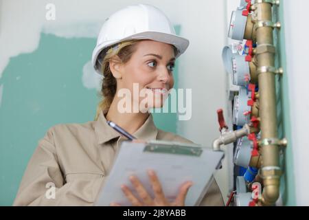 woman with clipboard inspecting plumbing installation Stock Photo