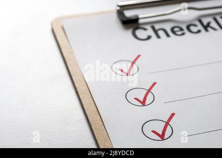 Checked checklist on a clipboard is on a bright desk Stock Photo