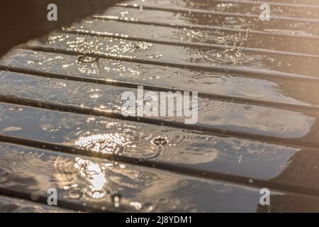 Rain patters on a garden table in the sunlight Stock Photo