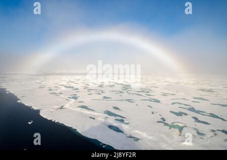 A rare fog bow hangs over sea ice in the Arctic Ocean Stock Photo