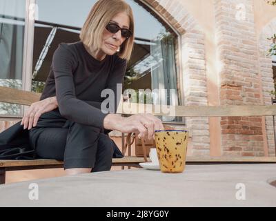 elegant fit lady having espresso coffee outdoors a sunny day Stock Photo