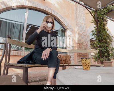 elegant fit lady having espresso coffee outdoors a sunny day Stock Photo