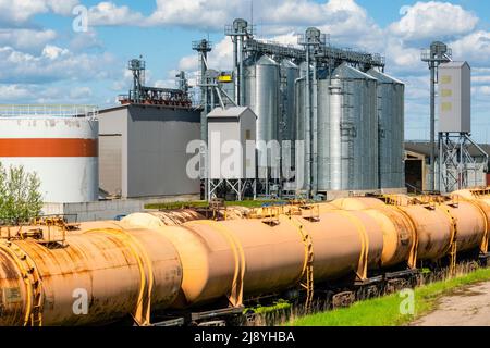 Grain silo, warehouse or depository next to railroad tracks with set of cargo tanks. Stock Photo