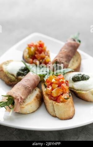 mixed crostini appetizers with parma ham, bruschetta and mozarella toppings Stock Photo