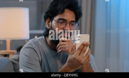 Arabic bearded 30s man in glasses at home with mobile phone talking on video call conference chat distance talking using smartphone for casual virtual Stock Photo
