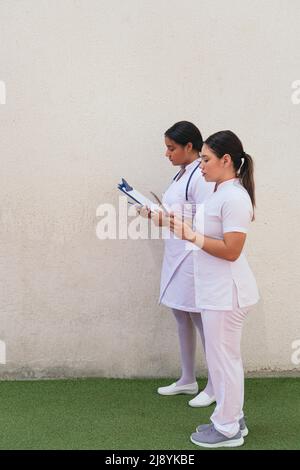 Latin Female nurses using digital tablet in hospital corridor Stock Photo