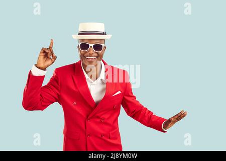 Cheerful and stylish dark-skinned showman on pastel light blue background has great idea for party. Stock Photo