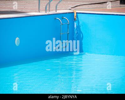 Pouring fresh water into swimming pool. Clear blue water refreshing disinfection purification, algae bacteria prevent. Summer active lifestyle, swim f Stock Photo