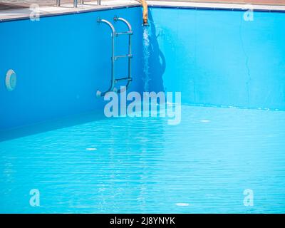 Pouring fresh water into swimming pool. Clear blue water refreshing disinfection purification, algae bacteria prevent. Summer active lifestyle, swim f Stock Photo