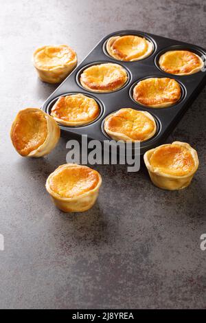 Freshly baked sweet Tarts Queijadas close-up in a baking dish on the table. vertical Stock Photo