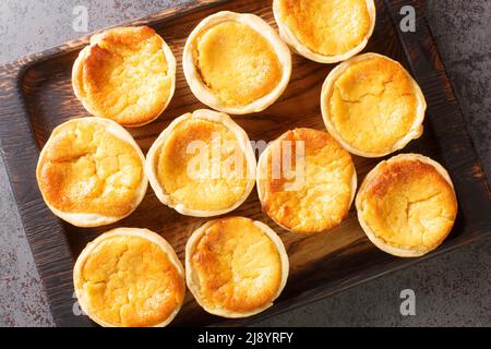 Portuguese cheese Tarts Queijadas are a sweet, creamy, traditional dessert close-up on a wooden tray on the table. Horizontal top view from above Stock Photo
