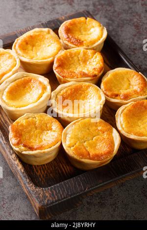 Queijadas Portuguese Cheesecake Tarts close-up on a wooden tray on the table. Vertical Stock Photo