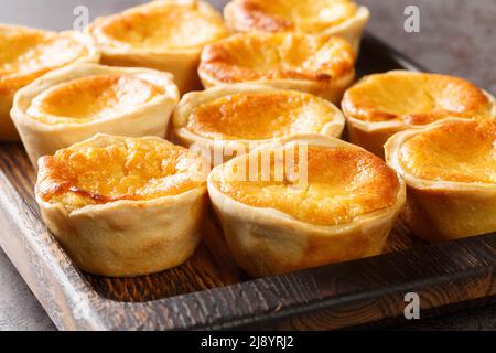 Queijadas de Sintra are sweet cheese tarts with a hint of cinnamon close-up on a wooden tray on the table. Horizontal Stock Photo