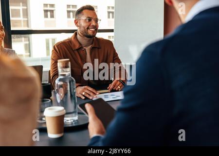 businesspeople having a meeting in a modern office. Group of multiethnic businesspeople having a discussion during their morning briefing. Happy young Stock Photo