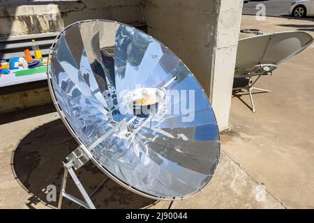 Cooking with sun energy, parabolic solar oven in the middle of cooking a dish thanks to solar energy Stock Photo