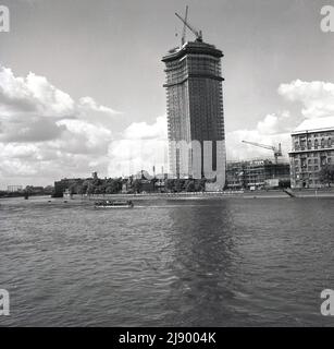 1962, historical, view from the river Thames of a new high-rise office building under construction on the South Bank of the river, London, England, UK. Built by John Mowlem & Co for the British engineering company, Vickers and originally known as Vickers House or Tower, it later became known as Millbank Tower.  Construction on this modern skyscraper started in 1959 and on completion in 1963, it became the tallest building in the UK at 387ft. In the 1990s, the building became famous as the headquarters of the Labour Party. It was Grade II listed in 1995. Stock Photo