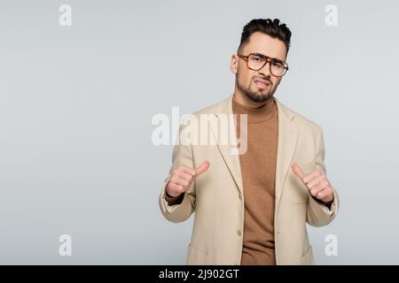 arrogant critic pointing at himself with thumbs isolated on grey Stock Photo