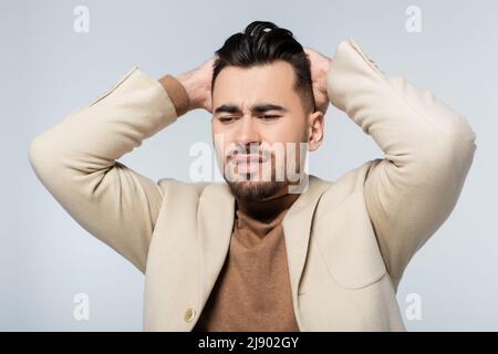 frustrated critic holding hands behind head isolated on grey Stock Photo