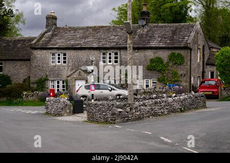 Quiet Conistone village centre (attractive C18 stone properties, walled road junction, signpost pointing) - Wharfedale, Yorkshire Dales, England, UK.