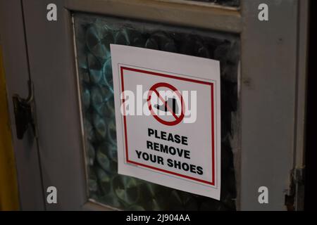 'Please remove your shoes' advice on a door Stock Photo